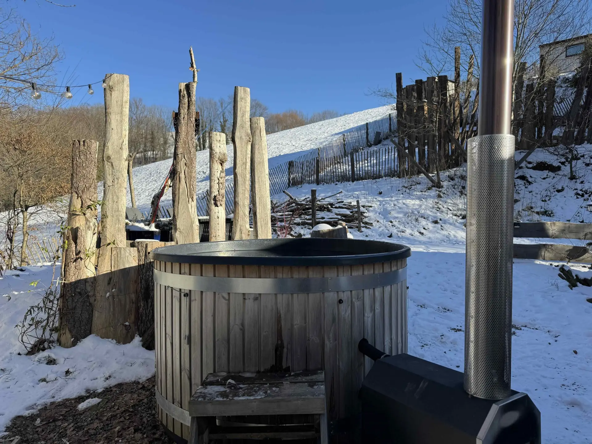 Bain nordique sur terrasse enneigée avec vue sur les hauteurs, Tiny House Petite Ourse
